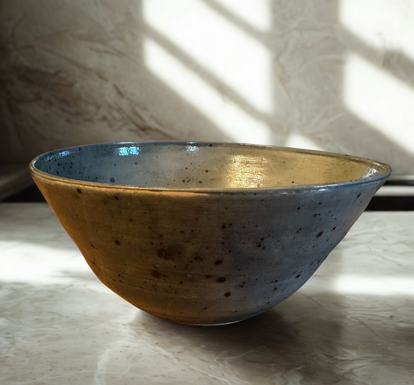 Ceramic bowl with speckled glaze on a textured surface