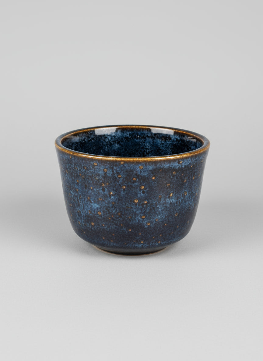 Blue ceramic pot with speckled texture on a light gray background
