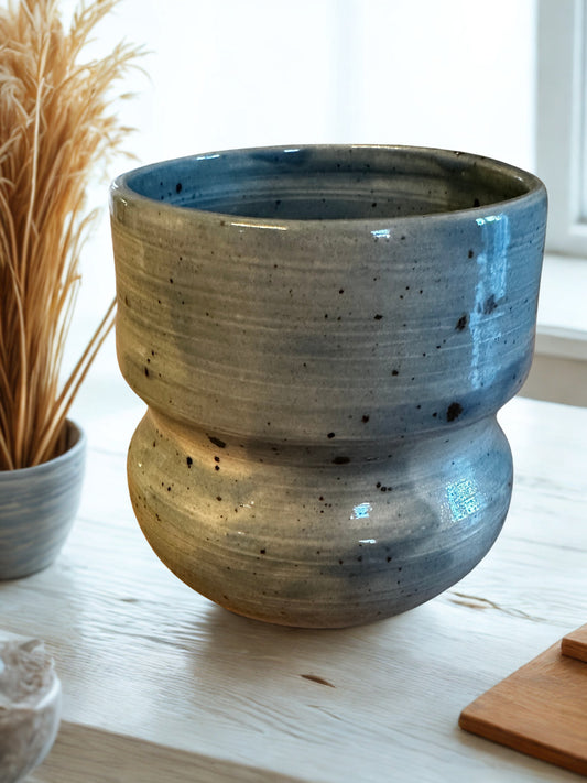 Blue speckled ceramic vase on a light wooden surface.