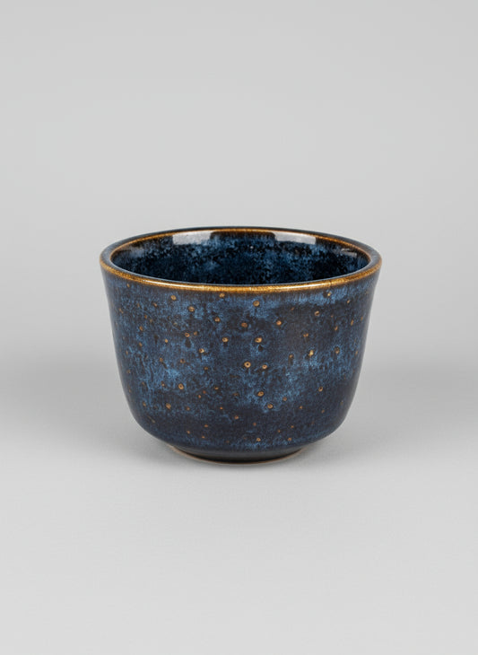 Blue ceramic pot with speckled texture on a light gray background